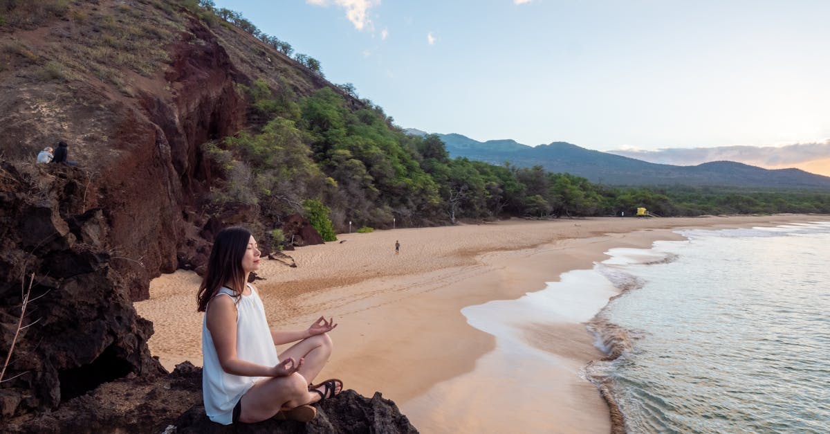 Jeune femme d'origine ethnique médite sur une plage déserte.
