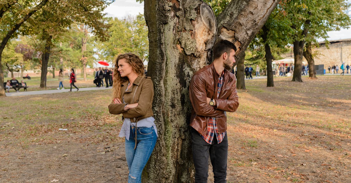 Un homme et une femme portant des vestes en cuir se tiennent debout sous un arbre.