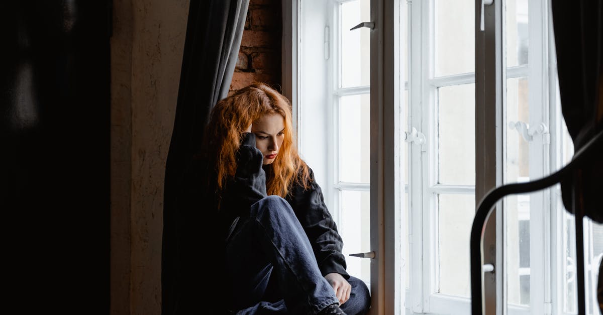 Femme en veste de cuir noir assise sur un sol en bois marron.