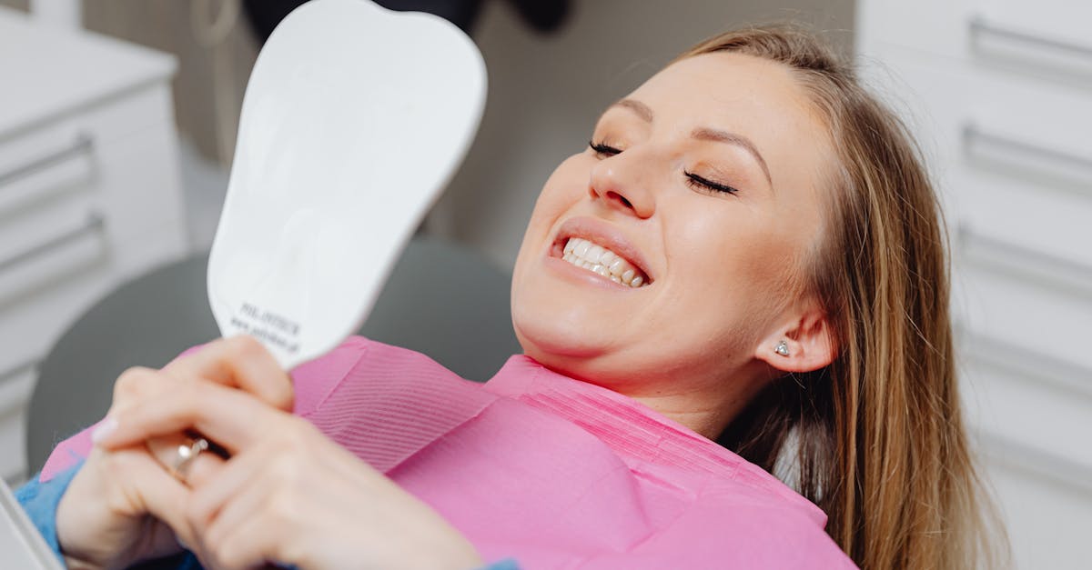 Femme souriante dans un fauteuil de dentiste se regardant dans le miroir