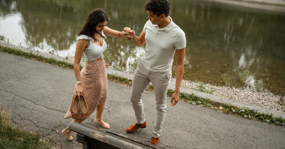 Un couple se promenant main dans la main le long d'un parc au bord de la rivière, savourant une journée paisible en plein air.