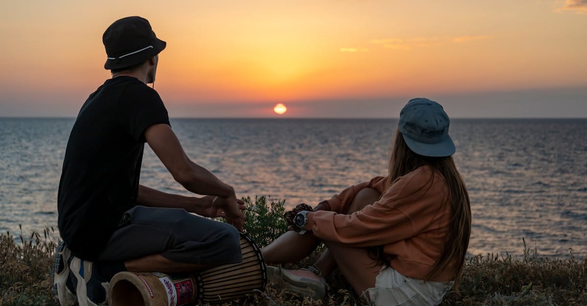 Un couple se détend au bord de l'océan, savourant ensemble un magnifique coucher de soleil, créant ainsi une atmosphère sereine et romantique.
