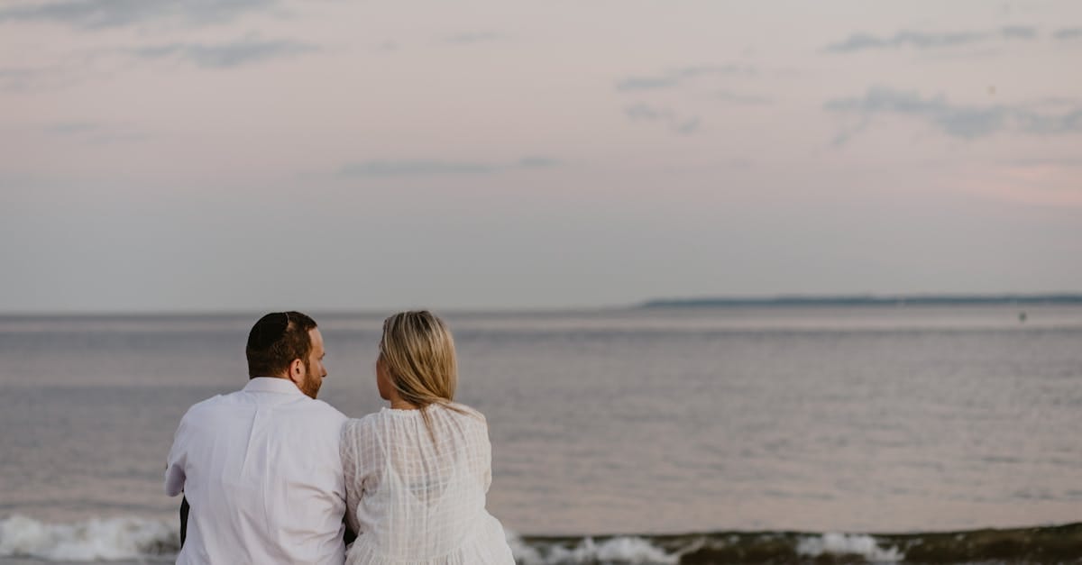 Un couple assis sur la plage, profitant d'une vue sereine sur le coucher de soleil au-dessus de l'océan.