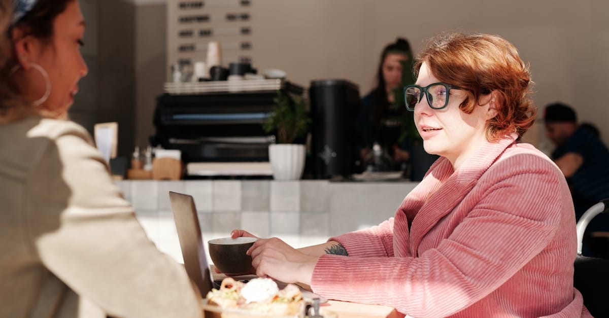 Deux femmes discutent autour d'un café et de petites collations dans une atmosphère lumineuse et accueillante d'un café.