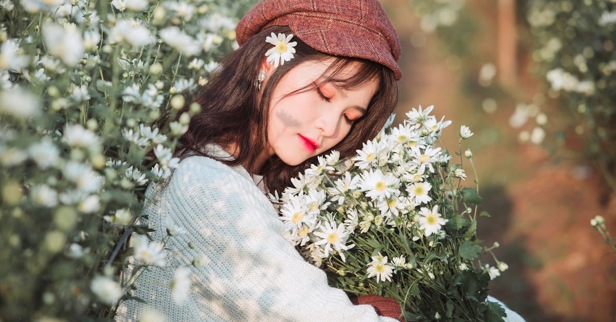 Une femme portant un béret enlace des marguerites blanches dans un cadre extérieur empreint de rêve.