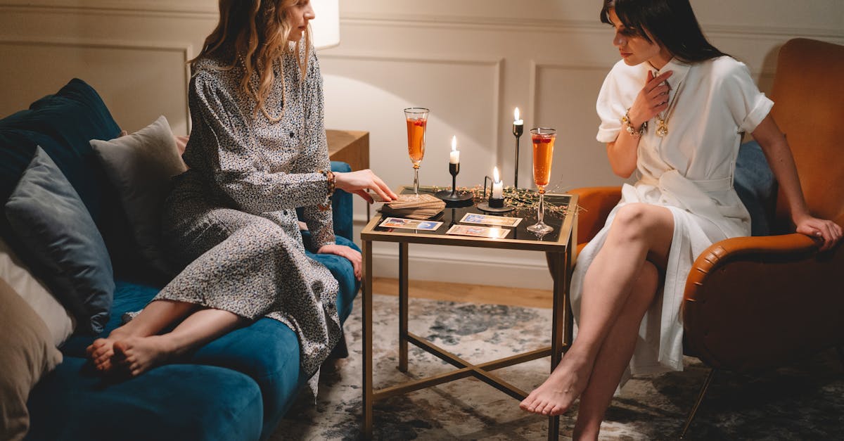 Deux femmes profitant d'une séance de tarot accompagnée de bougies et de vin dans un cadre intérieur chaleureux.