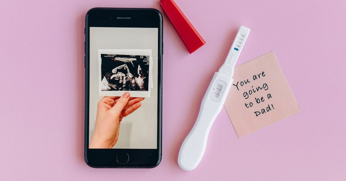 Fond rose avec un test de grossesse, une image d'échographie et un message pour un futur papa
