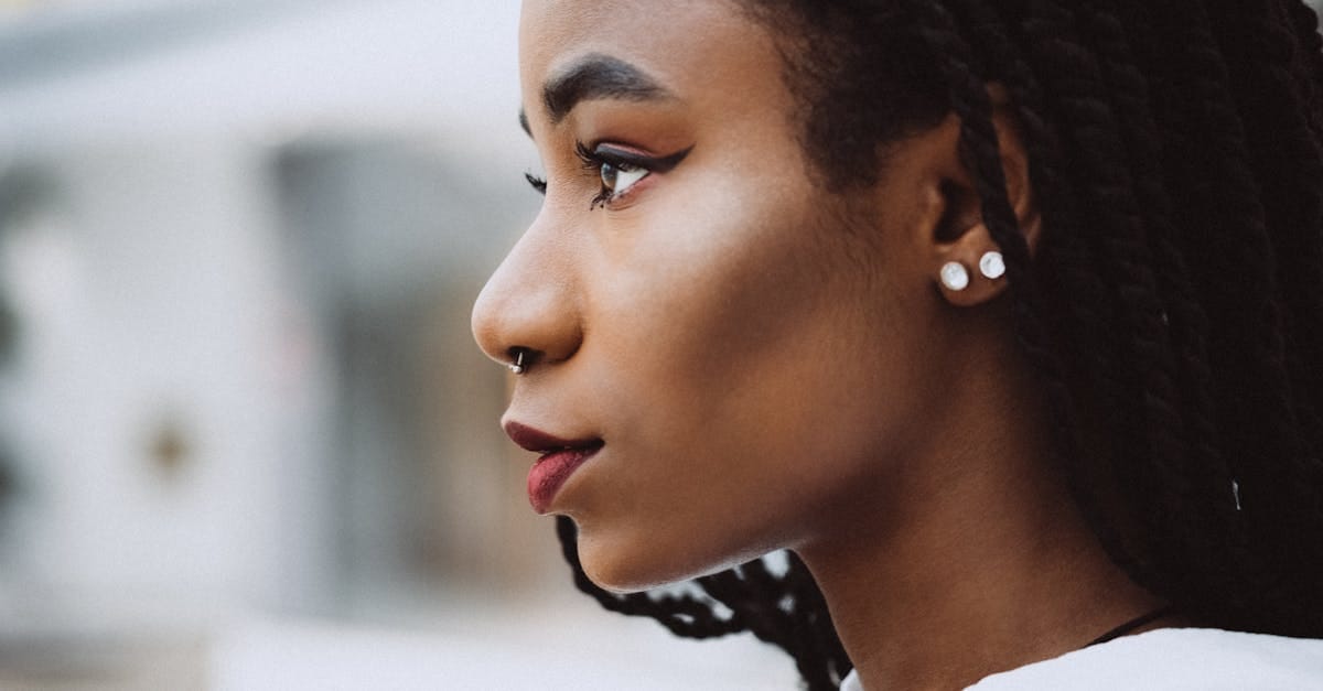 Vue en gros plan sur le côté d'une femme aux tresses et ornements, mettant en avant sa beauté naturelle et son style.