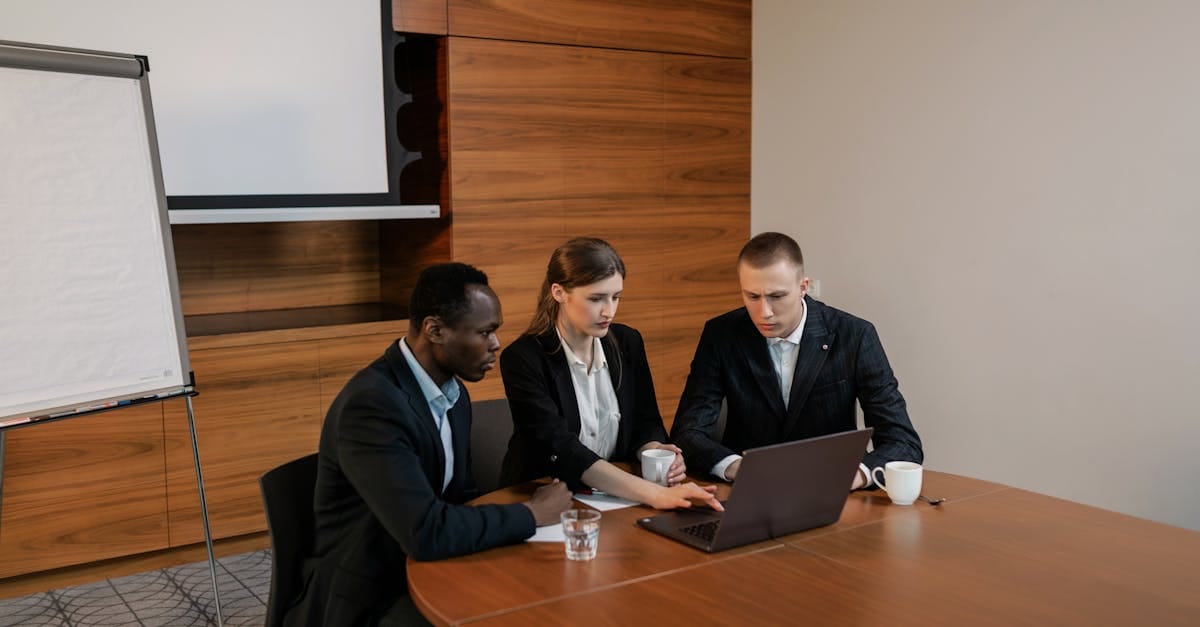 Un groupe de professionnels aux horizons variés collaborant sur un ordinateur portable lors d'une réunion en intérieur.