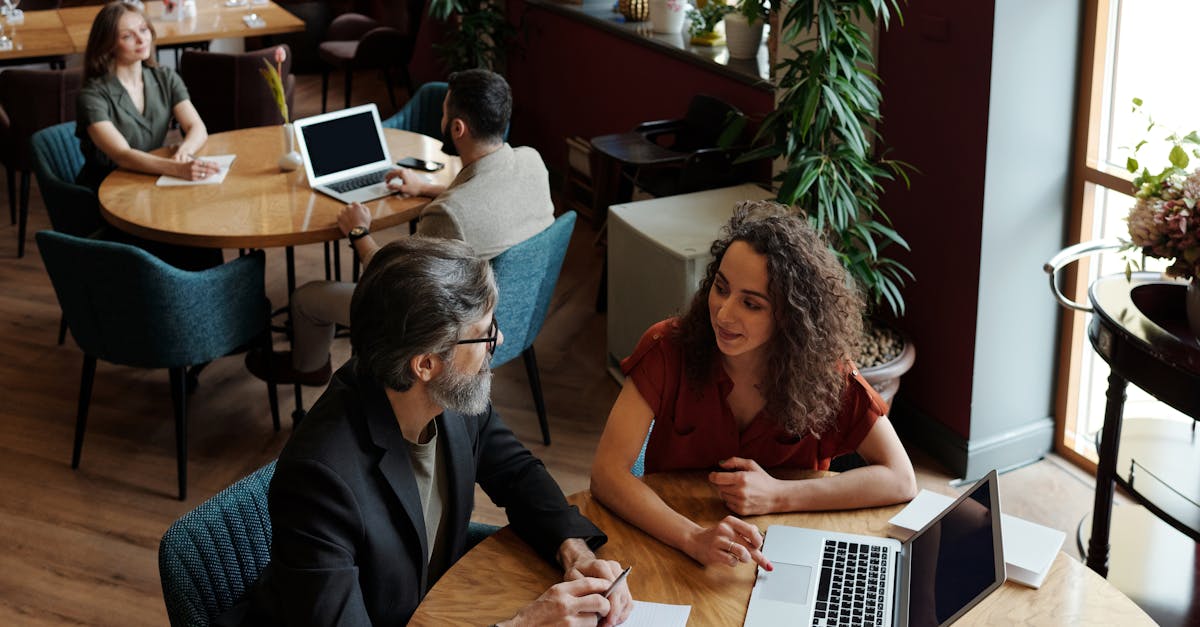 Des professionnels participant à une réunion collaborative dans un café chaleureux, échangeant sur des projets d'affaires.