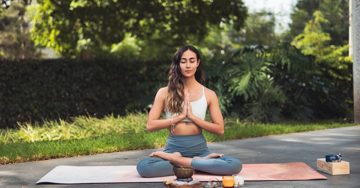 Une femme méditant sur un tapis de yoga en plein air, entourée de verdure, dégageant une atmosphère de calme et de sérénité.